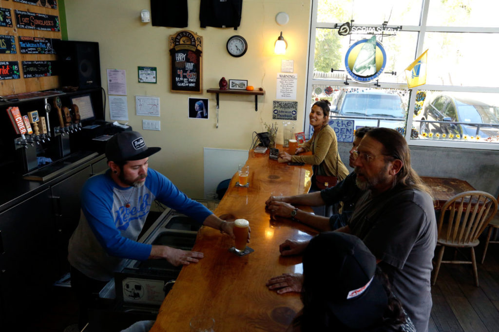 Front-end manager Jorge Smith, left, serves a beer to Ed Cron of Sebastopol at the Garden taproom inside Community Market at the Barlow in Sebastopol, California, on Wednesday, July 11, 2018. (Alvin Jornada / The Press Democrat)