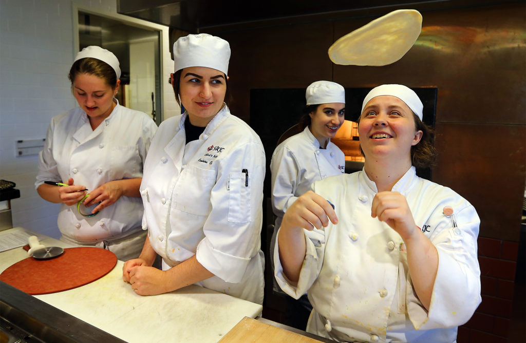 Cali Willis, right, tosses a pizza dough with fellow students Devin Green, Corinna Cellini, and Moon Levine in the kitchen at the SRJC Culinary Cafe. (JOHN BURGESS / The Press Democrat)