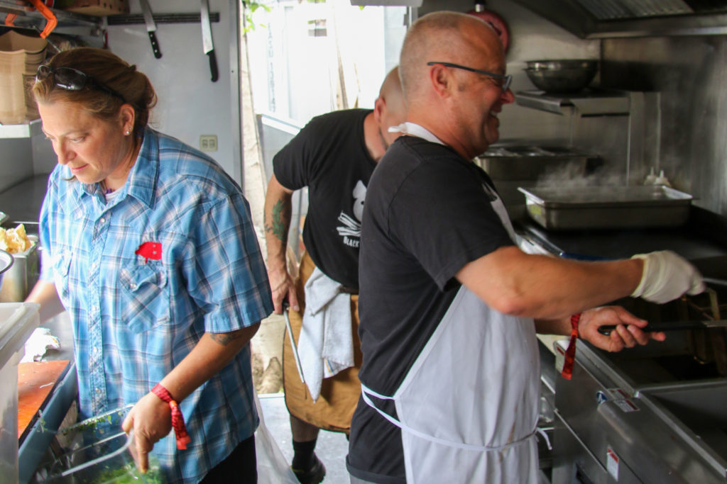 Chef Duskie Estes and John Stewart with their catering chef, Chris, on their Black Pig food truck in the VIP area at BottleRock 2019. Heather Irwin/PD