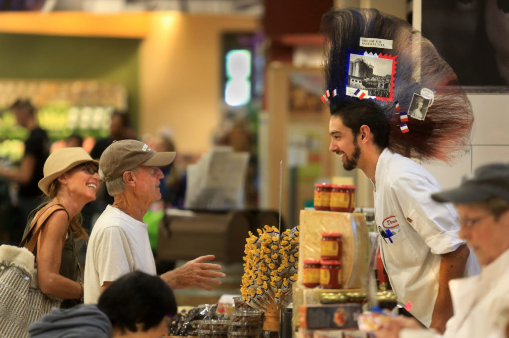Derek Glazzard, right, chats with Guerneville resident George White about his hair, Wednesday July 13, 2016. Glazzard works the cheese counter at Oliver's Market in Windsor and routinely celebrates coloring his mohawk to coincide with holidays around the world, including Bastille Day. (Kent Porter / Press Democrat) 2016