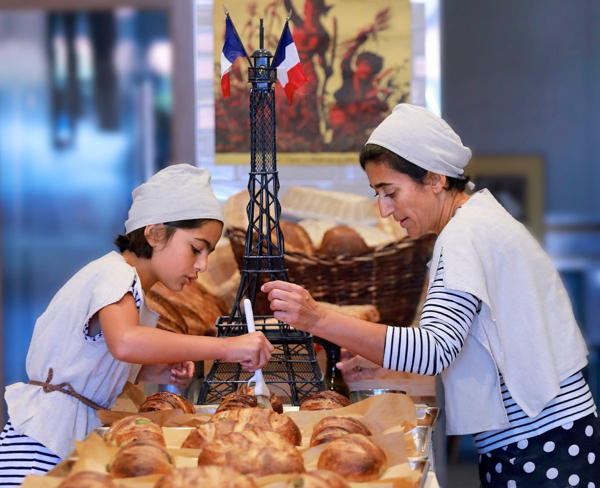 Soraya Salamati, 11, brushes on the olive oil over Pain aux olives before her mother Najine Shariat sprinkles a little salt on the loaves at Goguette Bread in Santa Rosa. (John Burgess/The Press Democrat)