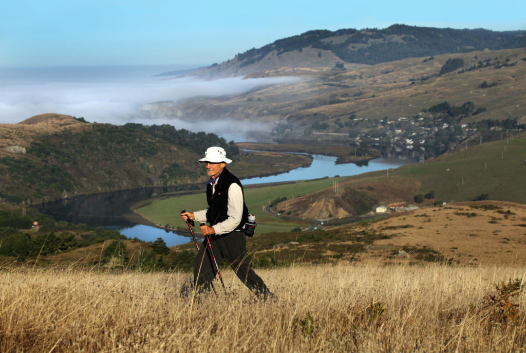 Larry Maniscalo, one of the leaders of the Oakmont Hiking Club, hikes up to Red Hill from Shell Beach with the mouth of the Russian River as a backdrop. (John Burgess / The Press Democrat)