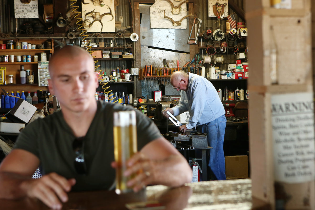 Mechanic Kenneth Altenreuther, right, works in the garage in the back of Ernie's Tin Bar. While people visiting the bar enjoy a cold beverage, they will notice that the bar and garage are next to one another. (Conner Jay/The Press Democrat)