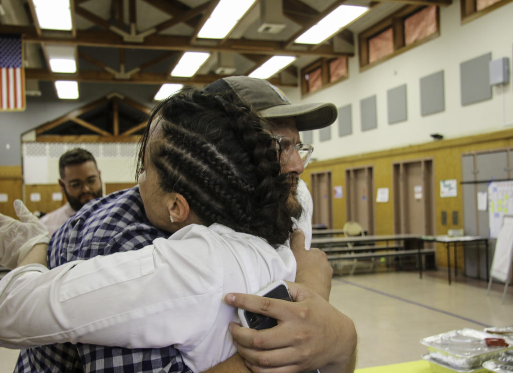 Domenica Catelli hugs Osvaldo Jimenez of Moustache Baked Goods at the Healdsburg evacuation center. Heather Irwin/PD