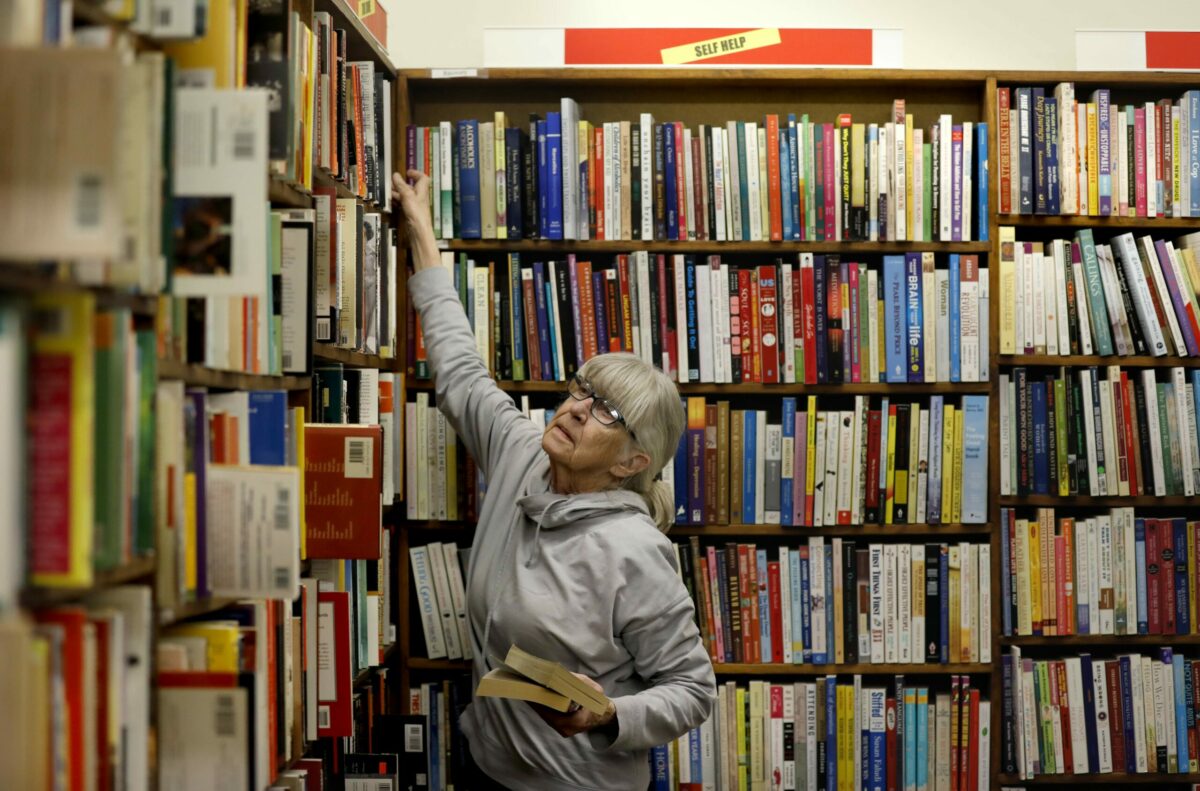 Employee Connie Del Bene puts books on the shelves at Paperbacks Unlimited in Santa Rosa on Monday, April 1, 2019. (Beth Schlanker/ The Press Democrat)
