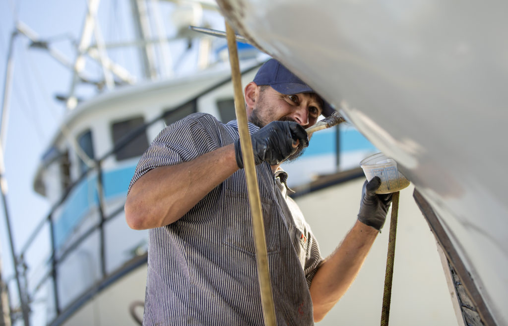 Capt. Mark Anello applies an epoxy while repairing the anchor guard on the Cape Ommaney, a 70 year-old wooden fishing boat he uses for salmon and black cod at the Spud Point Marina. (John Burgess)
