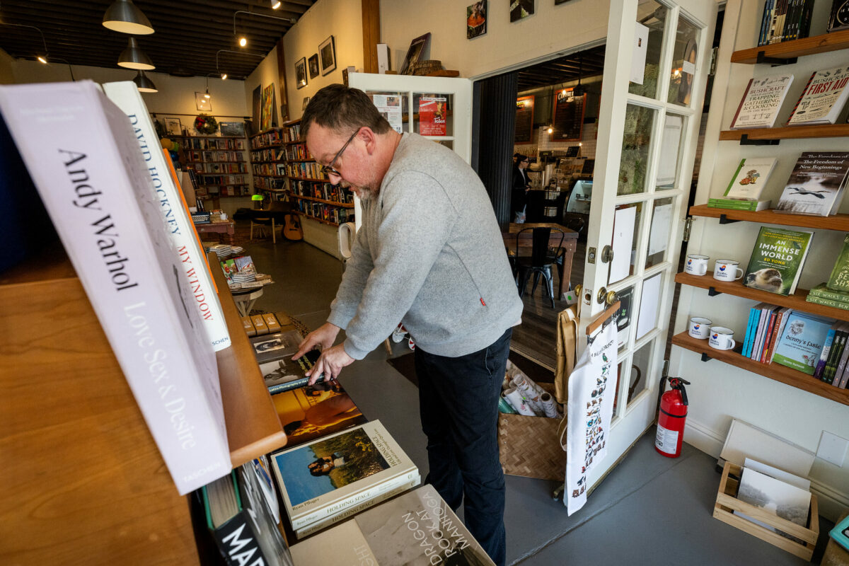 Owner Michael Rex tidies up books displays at Russian River Books and Letters in Guerneville Wednesday, December 13, 2022. (John Burgess/The Press Democrat)