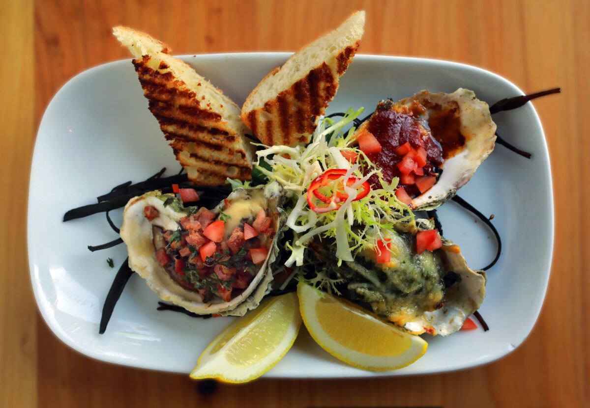 From left, Tasso Herb Grilled Oyster with cured ham and herb butter, Rockefeller Grilled Oyster with spinach, parmesan, Pernod, and garlic, Classic Chipotle BBQ Oyster all served with lemon and grilled baguette from The Shuckery in Petaluma. (John Burgess/The Press Democrat)