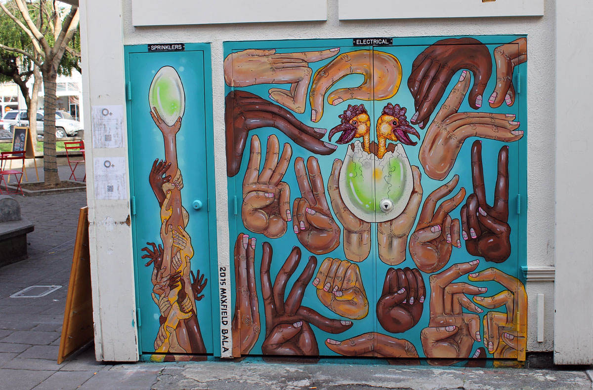 Artist Maxfield Bala, 22, painted these doors on a building on American Alley with a whimsical combination of arms, hands, fingers and eggs. (Chris Samson/For the Argus-Courier)