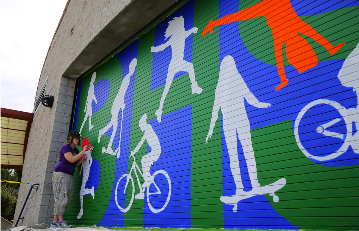 Artist Dana Lynn Vallarino works on a mural at Brook Haven School, in Sebastopol, on Thursday, July 2, 2015. Vallarino, an alumni of the school, worked with members of the school's Teens Go Green club to design the mural, which depicts silhouettes of students using green methods of transportation. (Christopher Chung/ The Press Democrat)