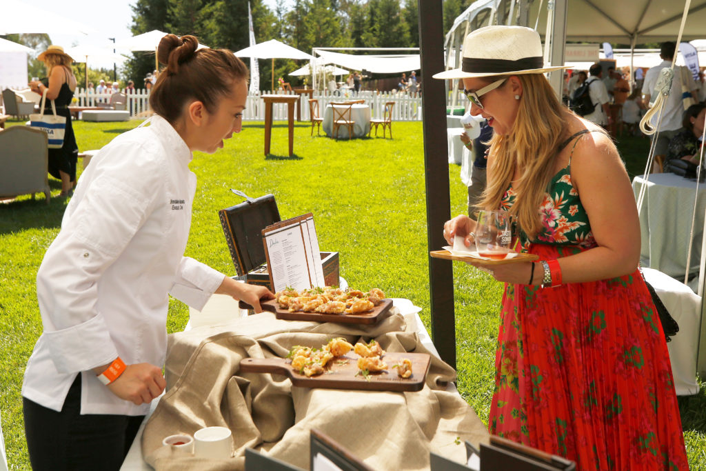 Chef Brendalee Vialpando, left, of Drake's Sonoma Coast at Bodega Bay Lodge offers Erin Boase of Austin, Texas a sample of Pork chicharon with Hamachi tartare during Taste of Sonoma at the Sonoma State University's Green Music Center, in Rohnert Park, California, on Saturday, August 31, 2019. (Alvin Jornada / The Press Democrat)