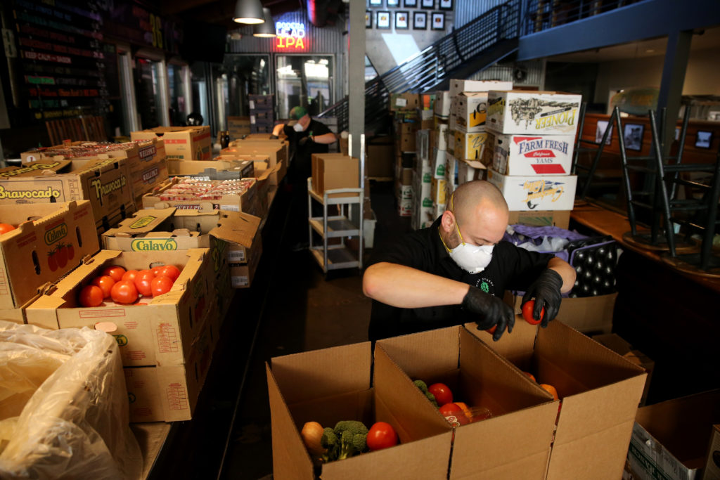 Third Street Aleworks co-owners Matthew Vella and Chris Frederick, rear, help pack boxes of produce for grocery boxes available for curbside pickup at the brewpub in Santa Rosa, California on Friday, May 1, 2020. (Beth Schlanker)