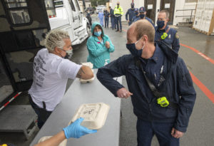 Santa Rosa Assistant Fire Marshal Paul Lowenthal bumps elbows with celebrity chef Guy Fieri at Memorial Hospital on Wednesday. Fieri brought family, friends and his 48-foot Guy’s Smokehouse Stagecoach mobile kitchen to feed first responders and hospital workers lunch. (photo by John Burgess/The Press Democrat).
