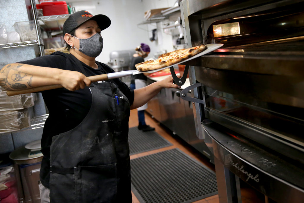 Leah Scurto, co-owner and executive pizza maker, puts a pizza in the oven at Pizza Leah in Windsor. (Beth Schlanker/The Press Democrat)