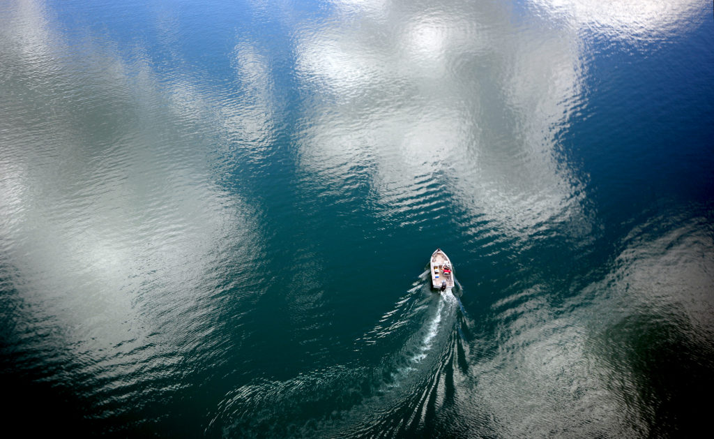 Puffy cumulus clouds are reflected in Lake Sonoma as a fisherman motors to his next spot, Wednesday, May 20, 2020. (Kent Porter / The Press Democrat) 2020
