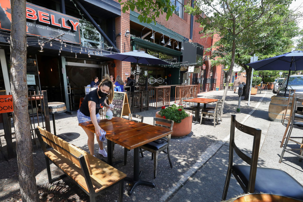 Rosmeri Caceres wipes down a table at Belly Left Coast Kitchen and Tap Room, where tables have been placed along the Fourth Street sidewalk to expand their outdoor patio seating area, in Santa Rosa on Friday, June 12, 2020. The City of Santa Rosa plans to close three blocks of Fourth Street to create a downtown promenade that will allow businesses to use sidewalk and street parking areas to seat customers outdoors. (Christopher Chung/ The Press Democrat)