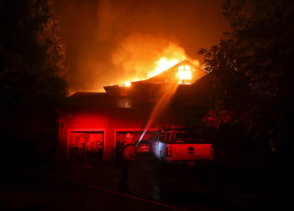 A firefighter puts water on a burning home on the corner of San Ramon Way and Mountain Hawk Drive in Santa Rosa on Monday, September 28, 2020. (Christopher Chung/ The Press Democrat)
