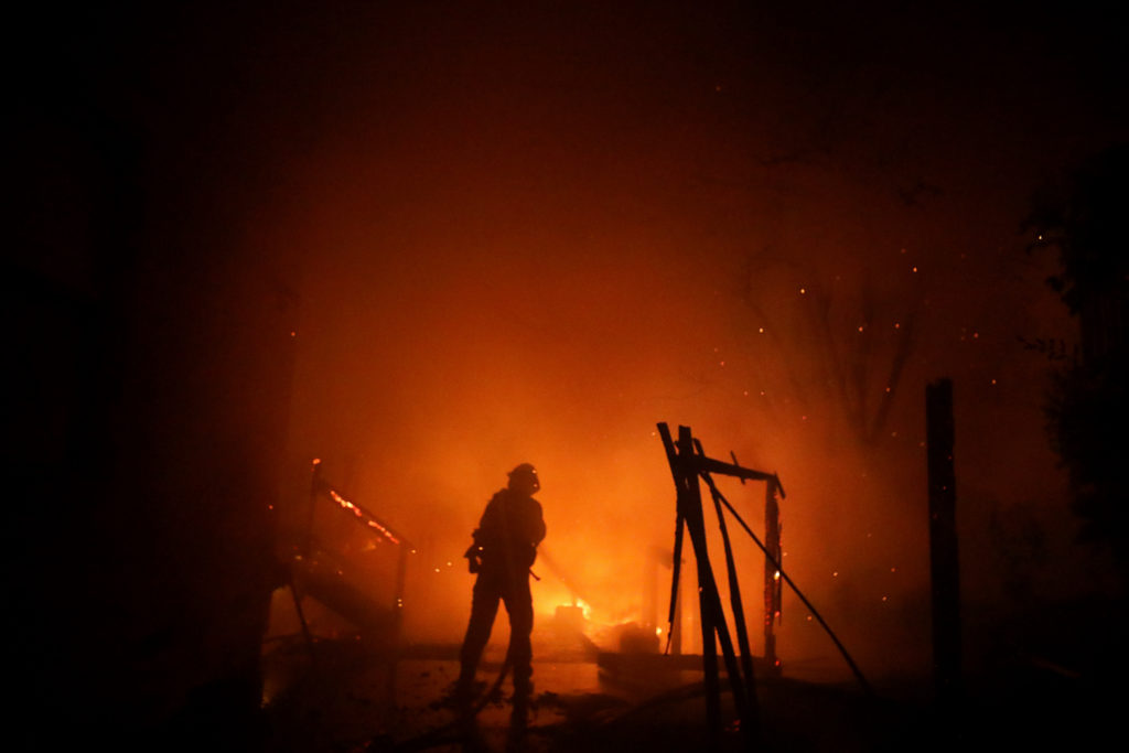 A firefighter is encompassed by thick smoke while trying to keep fire from reaching a structure on Mountain Hawk Drive in Santa Rosa on Monday, September 28, 2020. (Christopher Chung/ The Press Democrat)