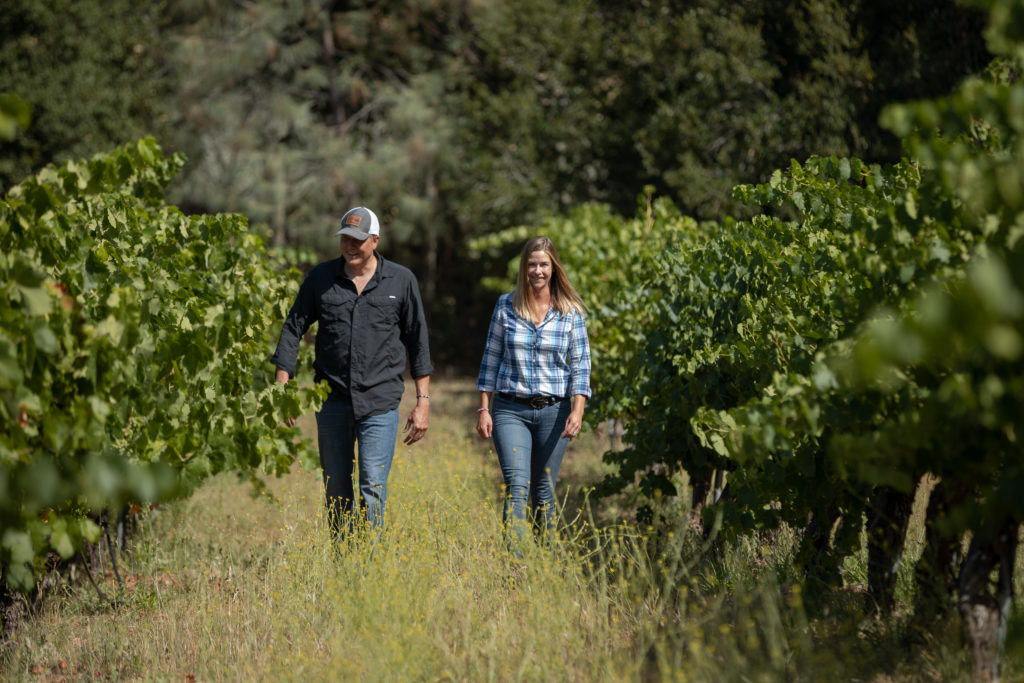 Emily Ernst and husband Greg, home winemakers walking through their vineyard.