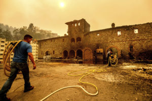 Winery workers Carlos Perez, left, and Jose Juan Perez extinguish hotspots at Castello di Amorosa, Monday, Sept. 28, 2020, in Calistoga, Calif., which was damaged in the Glass Fire. (AP Photo/Noah Berger)