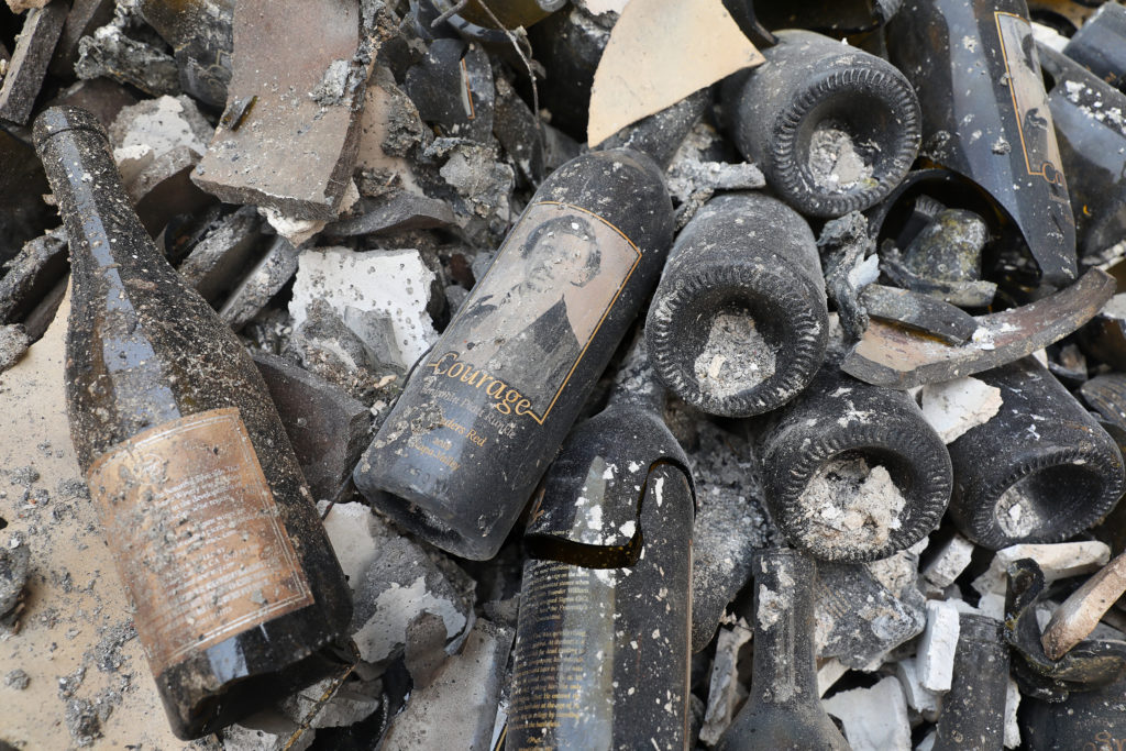 A bottle of Courage lays among the rubble of the Fairwinds Estate Winery, which was destroyed by the Glass incident fire, in St. Helena on Tuesday, September 29, 2020. (Christopher Chung/ The Press Democrat)