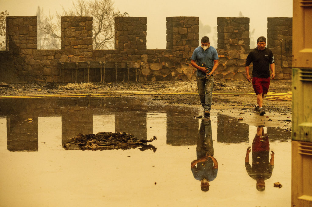 Winery worker Carlos Perez, left, walks, Monday, Sept. 28, 2020, in Calistoga, Calif., through Castello di Amorosa, which was damaged in the Glass Fire. Perez helped build the wine cellar that was scorched in the blaze. (AP Photo/Noah Berger)
