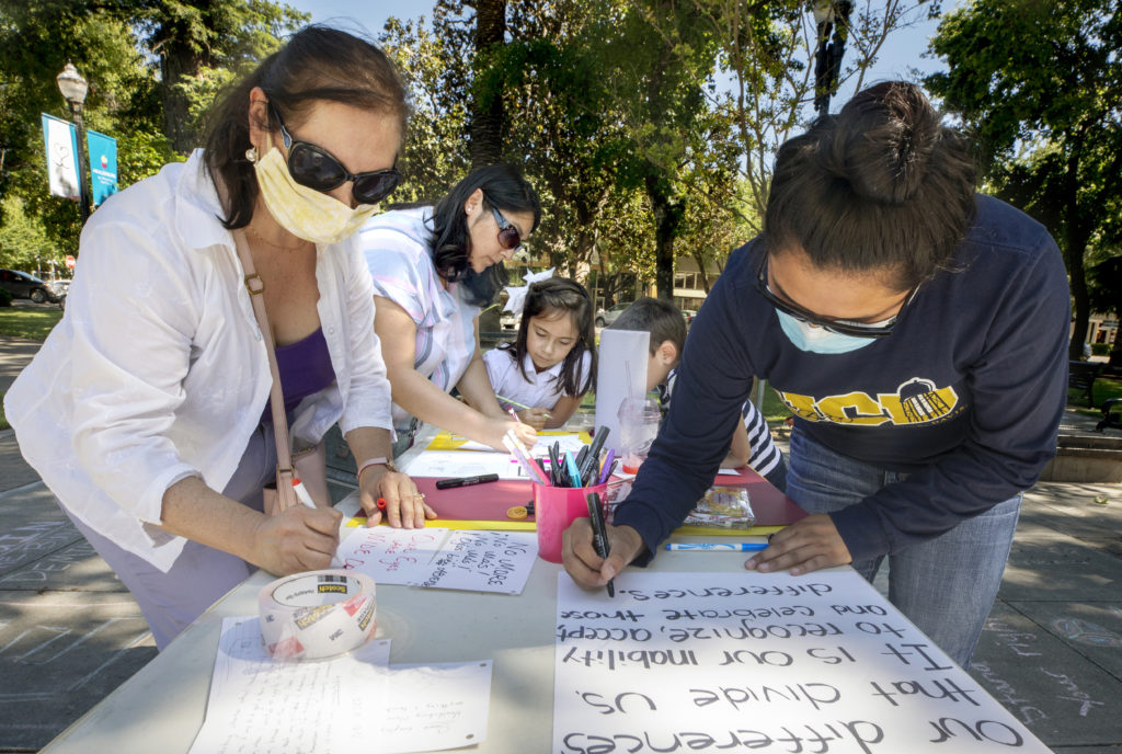 From left, Juanita Meza, Smirna Garcia, Abigail Mahoney, 7, and Abigail Gonzaga write about their experiences as a woman of color during the “What’s Your Experience With Racism In Healdsburg?” event Wednesday in the town square. (photo by John Burgess/The Press Democrat).