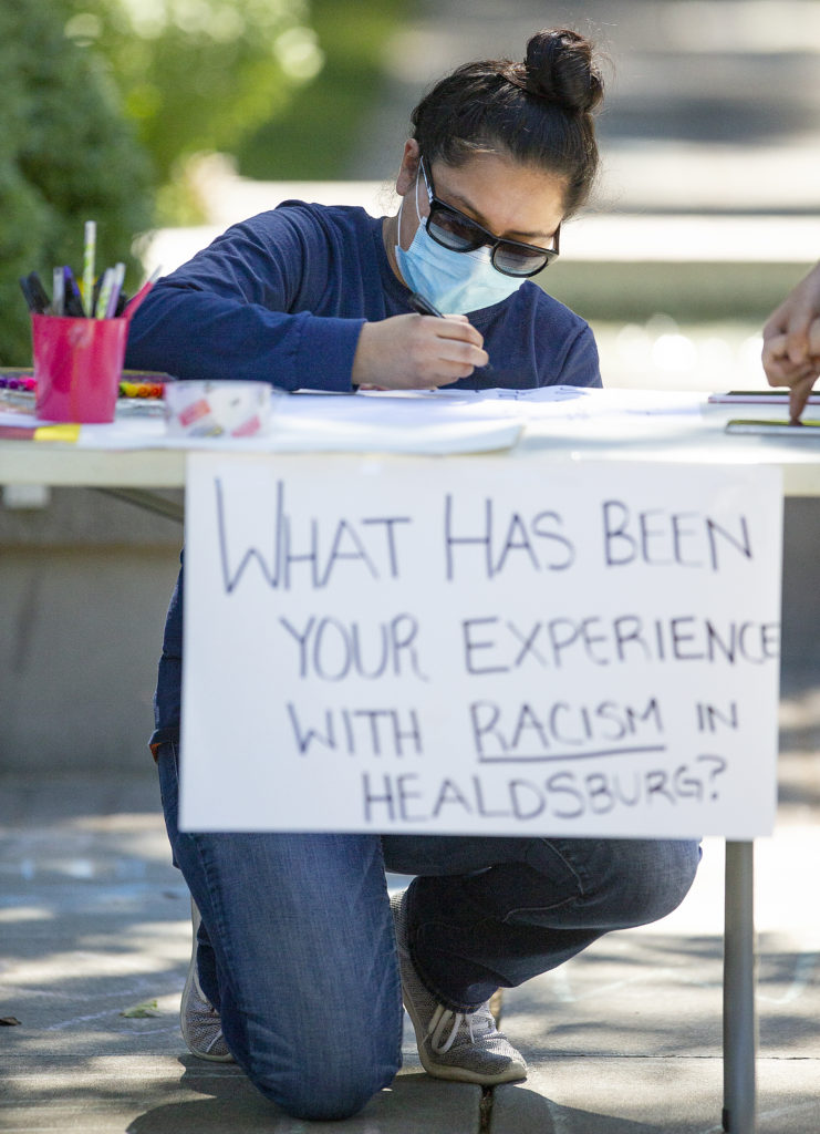 Abigail Gonzaga writes of her experiences as a woman of color during the “What’s Your Experience With Racism In Healdsburg?” event Wednesday in the town square. (photo by John Burgess/The Press Democrat).