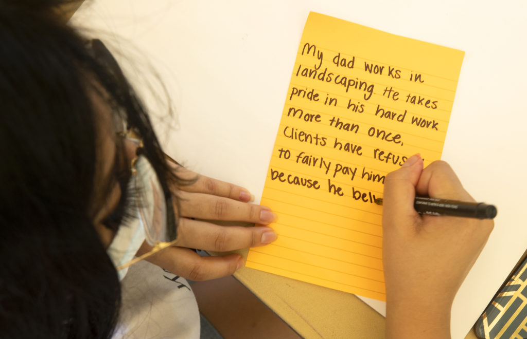 People who couldn’t make it to the “What’s Your Experience With Racism In Healdsburg?” event Wednesday in the town square sent in their experiences on social media. Cristal Garcia copies each note from Facebook onto cards to be displayed at a rally on Thursday night. (photo by John Burgess/The Press Democrat).