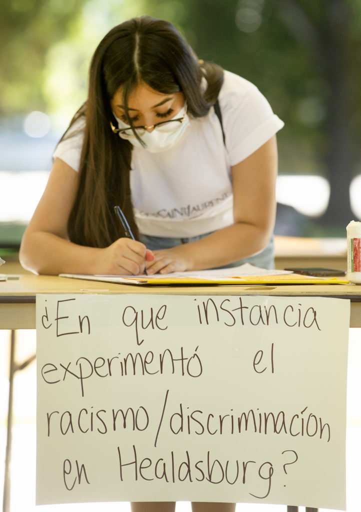 People who couldn’t make it to the “What’s Your Experience With Racism In Healdsburg?” event Wednesday in the town square sent in their experiences on social media. Cristal Garcia copies each note from Facebook onto cards to be displayed at a rally on Thursday night. (photo by John Burgess/The Press Democrat).