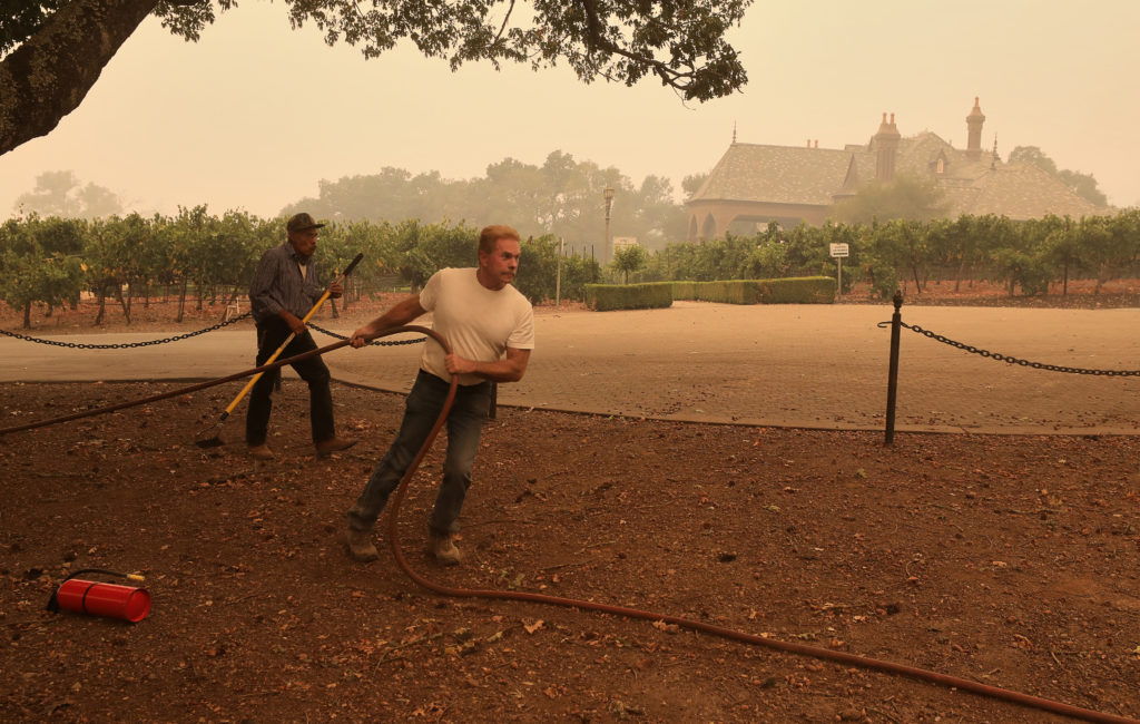 Steve Ledson, owner of Ledson Winery & Vineyards helps Cal Fire firefighters pull hose at his property in Santa Rosa on Monday, September 28, 2020. (Christopher Chung/ The Press Democrat)