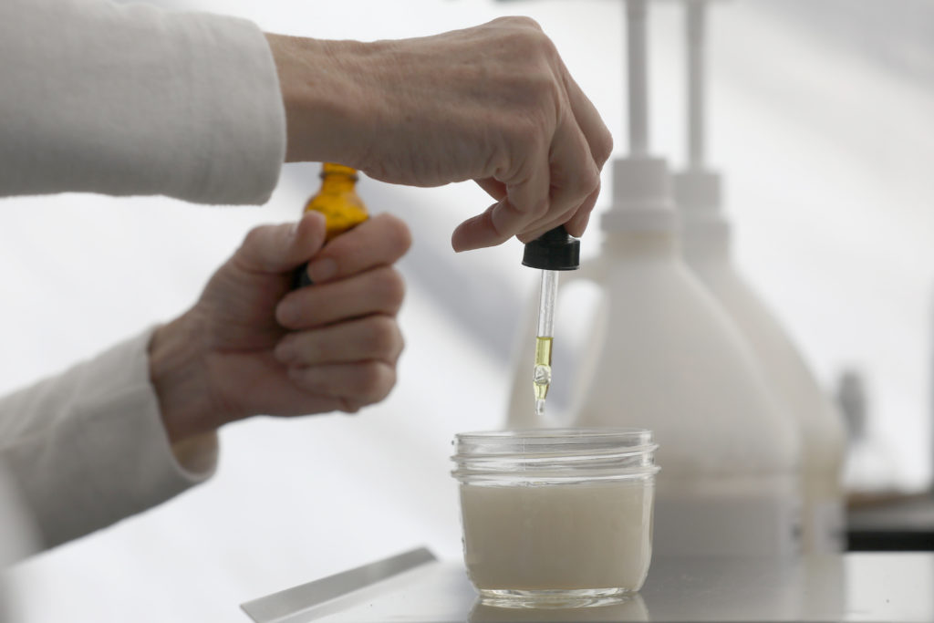 Joan Ayers, owner of Homebody Refill, adds orange essential oil to a mason jar of unscented organic shampoo for a customer at the Petaluma East Side Farmers' Market in Petaluma, Calif., on Tuesday, November 10, 2020. (Beth Schlanker / The Press Democrat)