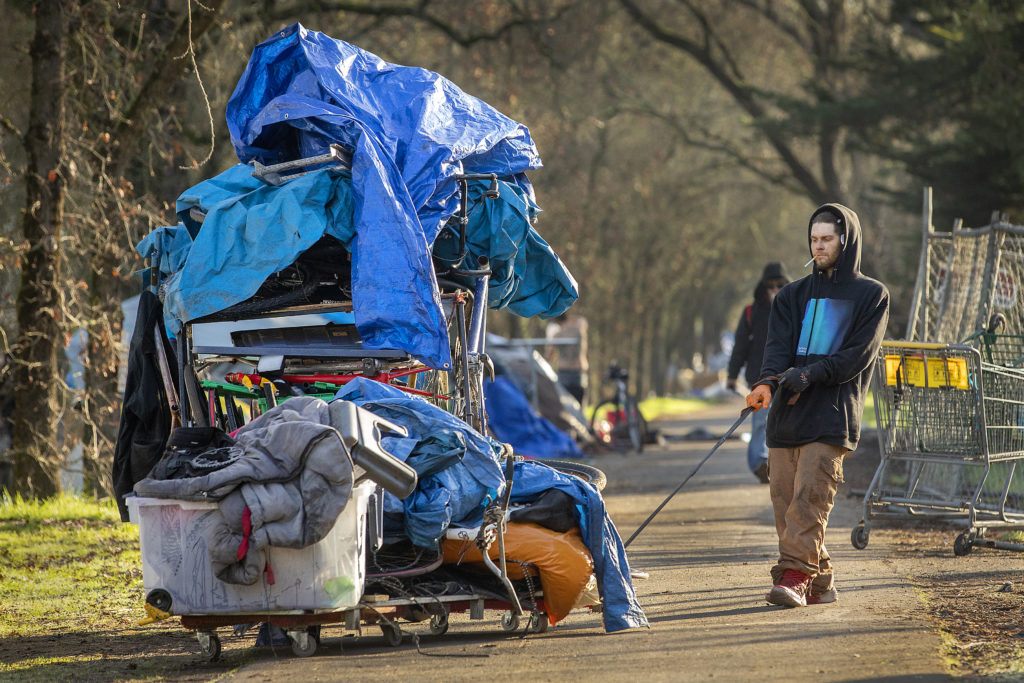 A homeless resident pulls a cart loaded with his belongings away from his campsite along the Joe Rodota trail in Santa Rosa on Friday. Local authorities swept the area on Friday, evicting any residents who remained. (photo by John Burgess/The Press Democrat)