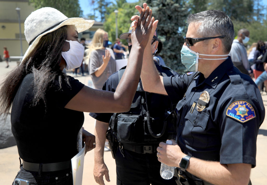 Rohnert Park Peaceful March for Justice organizer Jackie Elward and Rohnert Park Department of Public Safety's deputy chief of police Aaron Johnson, share a high five Rohnert Park, Saturday, June13, 2020. (Kent Porter / The Press Democrat) 2020