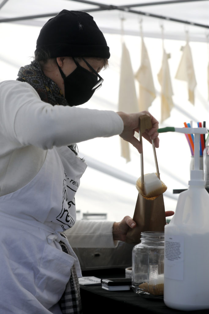 Joan Ayers, owner of Homebody Refill, bags up a deodorant cube for a customer at her booth at the Petaluma East Side Farmers' Market in Petaluma, Calif., on Tuesday, November 10, 2020. (Beth Schlanker / The Press Democrat)