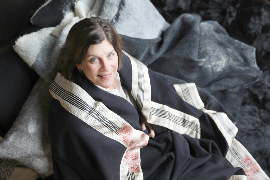 Jessica Switzer Green, founder of JG Switzer, is wrapped in a Now Voyager blanket from the Legends Collection, on top of Heritage Sheep Collection bedding. JG Swtizer produces luxury blankets and bedding out of a workshop at The Barlow, in Sebastopol. (Christopher Chung / The Press Democrat)