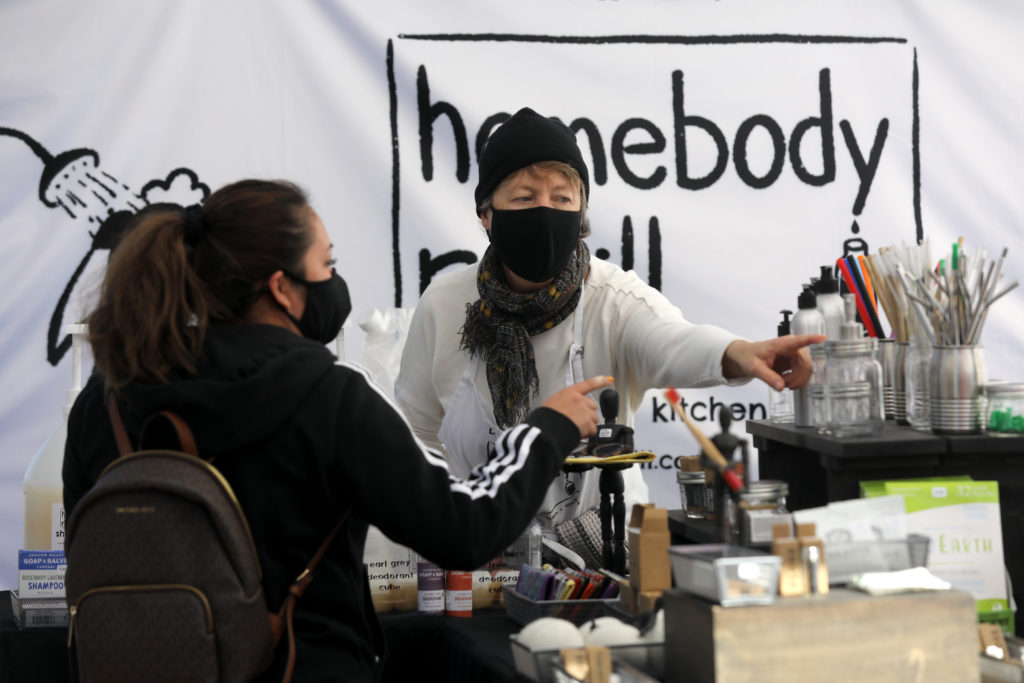 Joan Ayers, owner of Homebody Refill, helps customer Yazmin Martinez get a refill of shampoo at her booth at the Petaluma East Side Farmers' Market in Petaluma, Calif., on Tuesday, November 10, 2020. (Beth Schlanker / The Press Democrat)