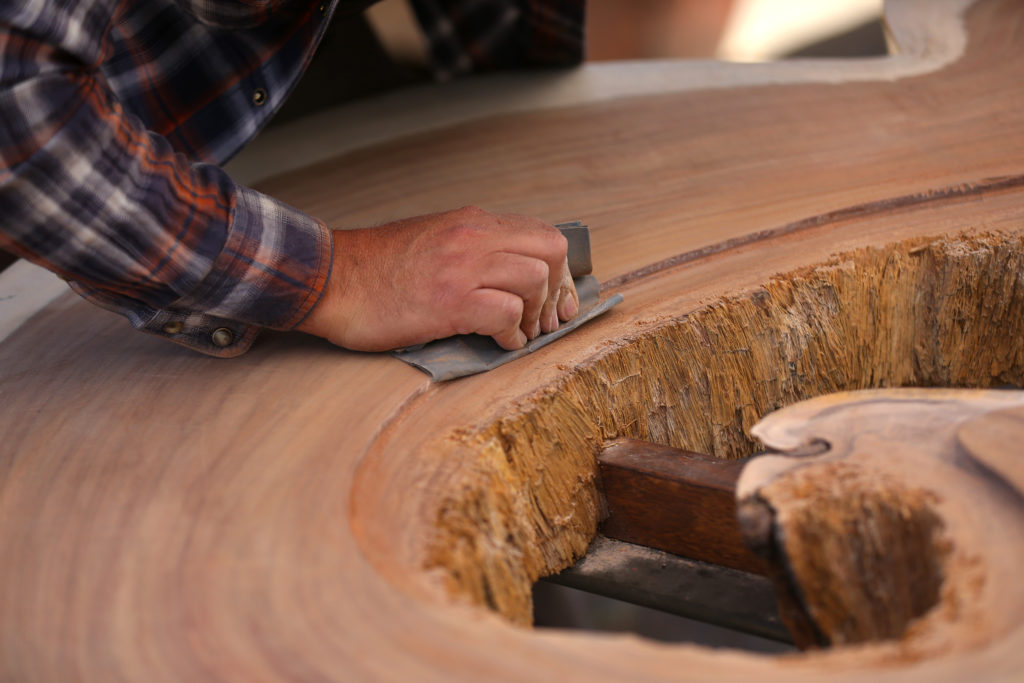 Jorge Martinez smooths down a section of a Parota tree where glass will be inlaid while making a table at his Wine Country Decor store in Santa Rosa. (Christopher Chung/The Press Democrat)
