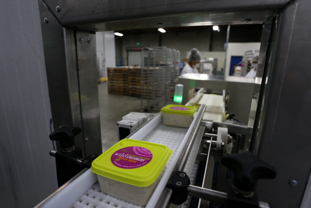 Packages of vegan French onion dip move through the production line at Wild Brine Creamery in Santa Rosa, Calif., on Tuesday, August 17, 2021. (Beth Schlanker/The Press Democrat)