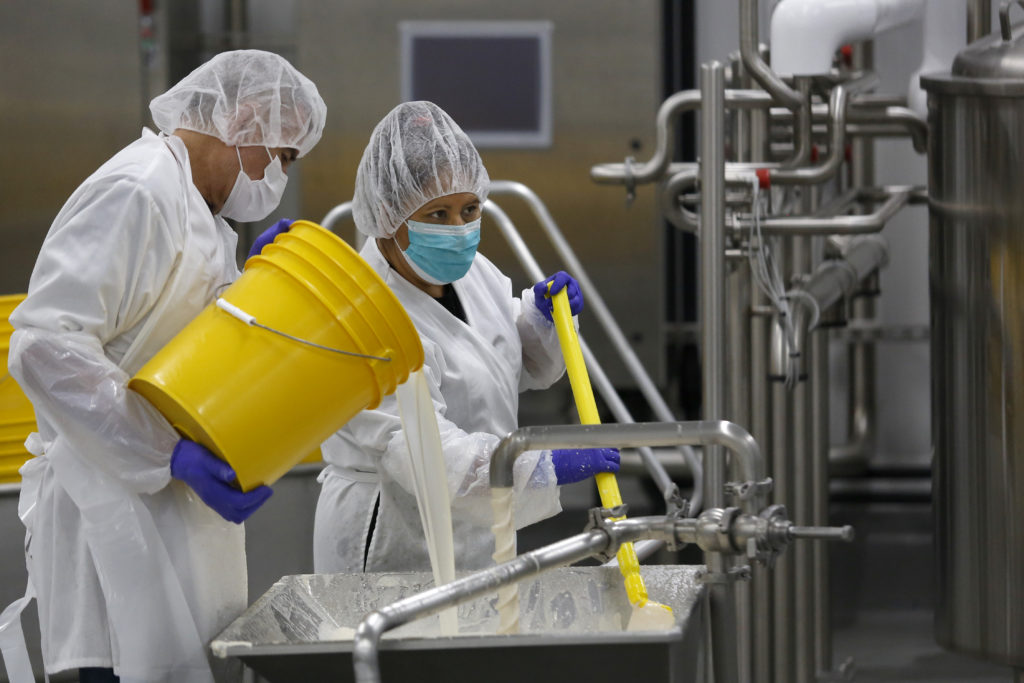 Employees Ernesto Ayala, let, and Leticia Rojas add ingredients to an emulsifier as they make vegan French onion dip at Wild Brine Creamery in Santa Rosa, Calif., on Tuesday, August 17, 2021. (Beth Schlanker/The Press Democrat)