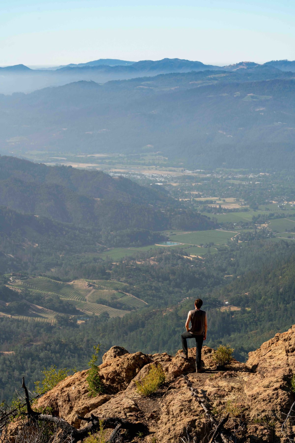 A man stands on a rocky edge looking out over the valley beneath Mt. St Helena in California