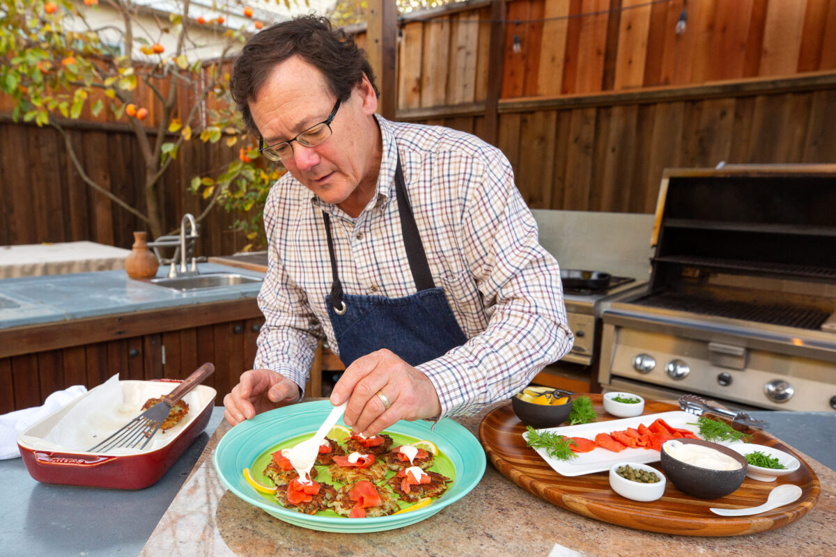 Chef Bruce Riezenman garnishes potato latkes with citrus-cured salmon, creme fraiche, dill, capers, and lemon at his home in Santa Rosa, California, on Wednesday, December 2, 2020. (Alvin A.H. Jornada / The Press Democrat)