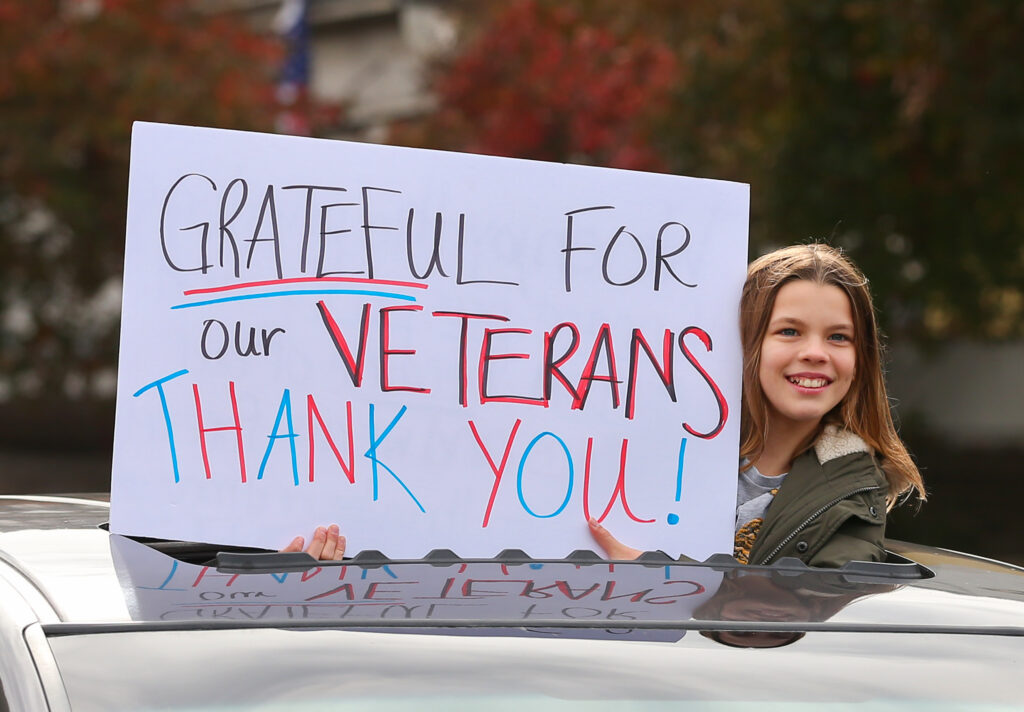 A Veterans Day procession participant holds up a sign through a car's sunroof in Petaluma on Wednesday, November 11, 2020. The traditional Veterans Day Parade had to be significantly scaled down due to the coronavirus pandemic. (Christopher Chung/ The Press Democrat)