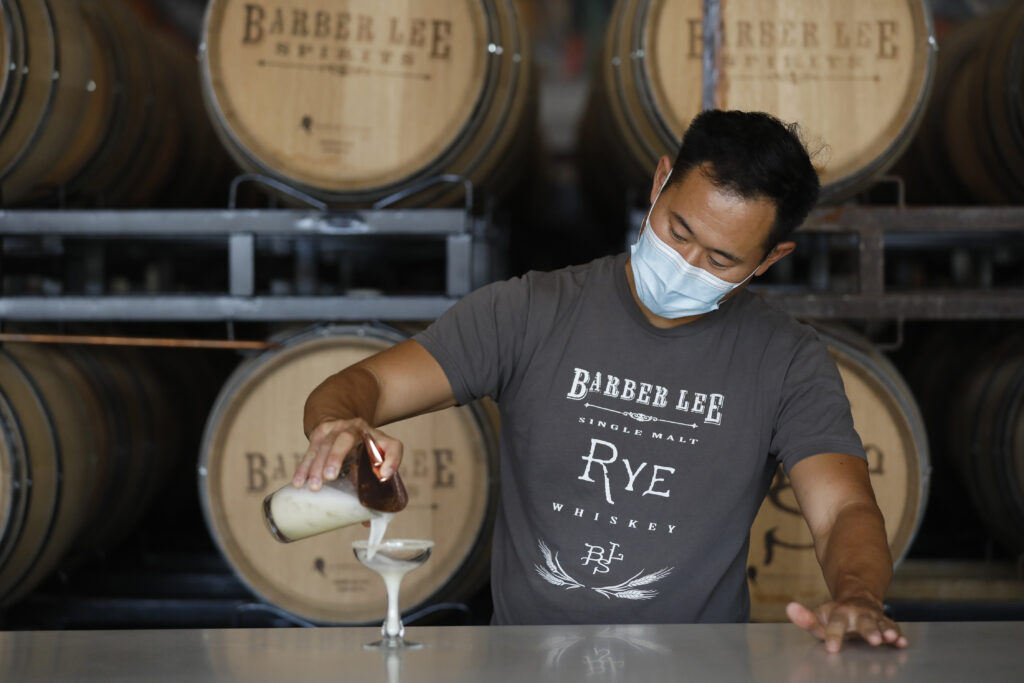 Aaron Lee, co-owner of Barber Lee Spirits, pours a Sicilian Sting, a mix of grappa, honey, lemon juice, egg white, with a chamomile sugar rim, in Petaluma, Calif., on Thursday, December 2, 2021. (Beth Schlanker/The Press Democrat)