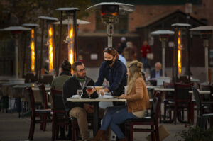 Tracy Emerson serves drinks to guests, Kevin and Jamie Pottorff, at a riverfront table on Water Street in Petaluma where Cucina Paradiso and other downtown restaurants have set up outdoor dining. (Crissy Pascual/Petaluma Argus-Courier)