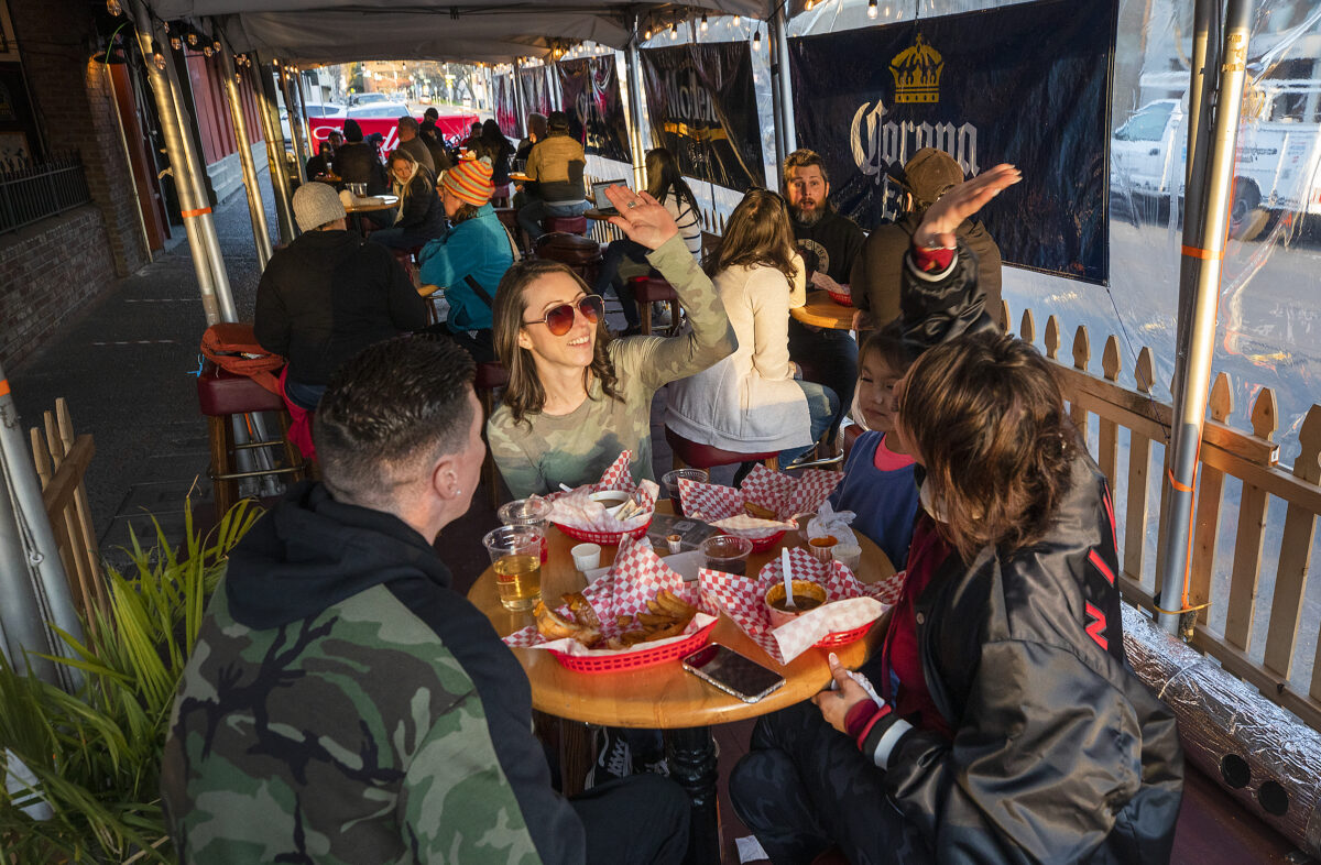 Krystal Camp, left, and Crystal Olivarez high five over their first outside restaurant meal since the stay at home order at Ausiello's 5th Street Bar and Grill on Monday, January 25, 2021. (Photo by John Burgess/The Press Democrat)