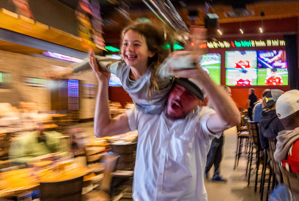 Matt Carlson gives Taylor Barlow, 7, a flying victory lap after a U.S. first half goal against Wales in the first round of the World Cup at the Victory House in Epicenter Santa Rosa Monday, November 21, 2022. (John Burgess/Press Democrat)