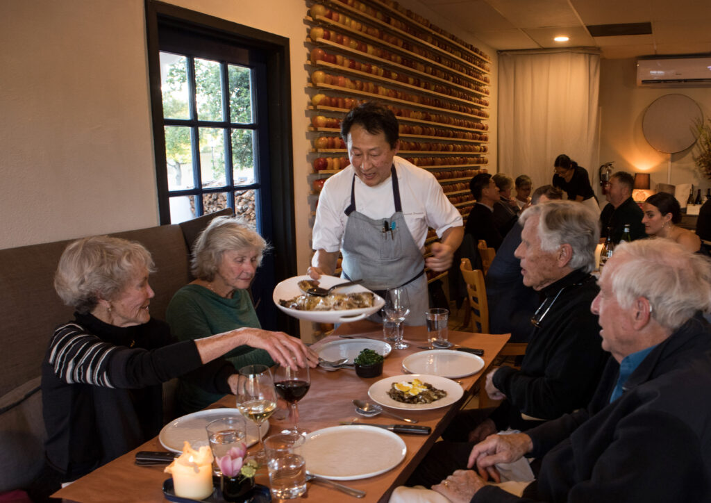 Co-owner, Joshua Smookler, serves a large turbot fish to couples, from left, Holly Kyle, of Sonoma, Patty Straus, of Cambridge, Mass., Steve Kyle, of Sonoma, and David Straus, of Cambridge, Mass., at, Animo, in Sonoma, Calif., on Wednesday, March 30, 2022. (Photo by Darryl Bush / For The Press Democrat)