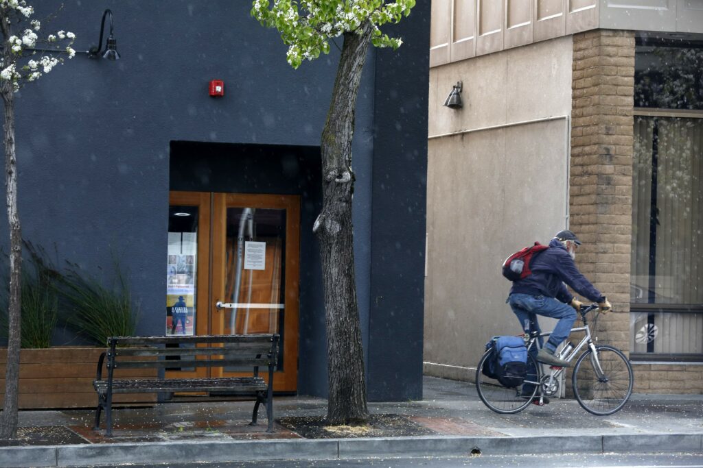A bicyclist rides past Ruin Cocktail Bar which is closed due to COVID-19 in Sebastopol, California on Sunday, March 22, 2020. (Beth Schlanker/The Press Democrat)