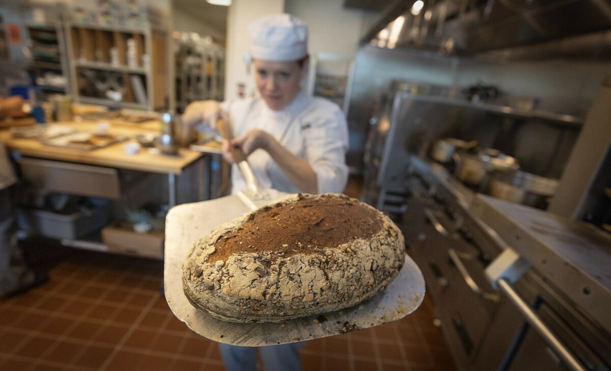 Kathryn Shunn pulls a loaf of whole wheat seeded bread in the production baking class at the SRJC Culinary Arts Center. (John Burgess/The Press Democrat)